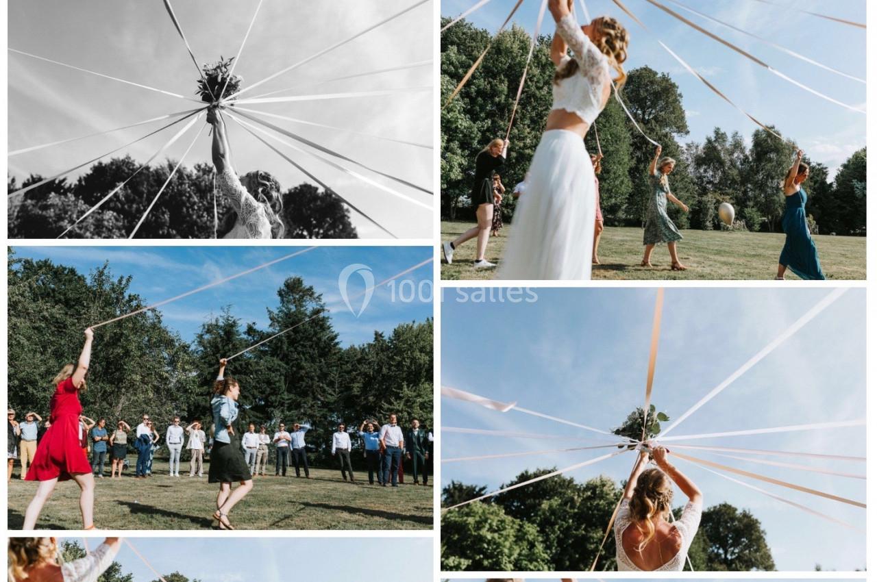 Des personnes dansent en extérieur autour d'un mât décoré, tenant des rubans colorés tendus vers le ciel.
