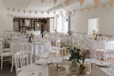 Centre de table floral avec fleurs séchées et pampas, entouré de couverts et cadeaux emballés sur une nappe blanche.