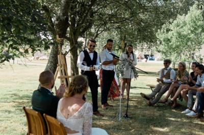 Centre de table floral avec fleurs séchées et pampas, entouré de couverts et cadeaux emballés sur une nappe blanche.