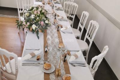 Centre de table floral avec fleurs séchées et pampas, entouré de couverts et cadeaux emballés sur une nappe blanche.