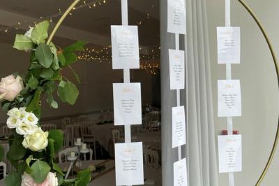 Centre de table floral avec fleurs séchées et pampas, entouré de couverts et cadeaux emballés sur une nappe blanche.