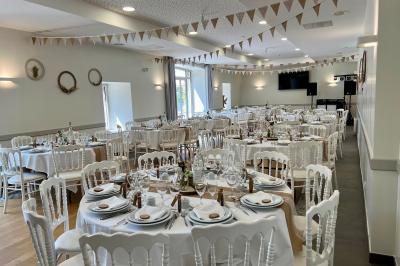 Centre de table floral avec fleurs séchées et pampas, entouré de couverts et cadeaux emballés sur une nappe blanche.
