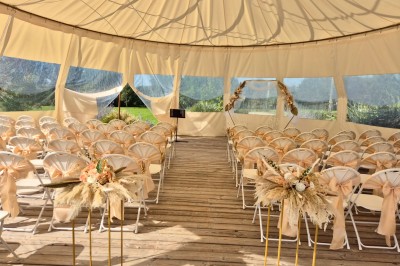 Centre de table floral avec fleurs séchées et pampas, entouré de couverts et cadeaux emballés sur une nappe blanche.