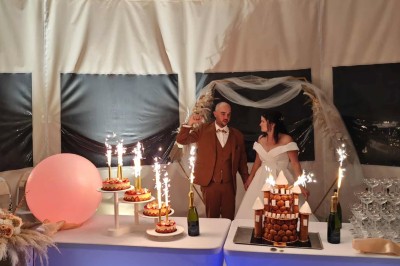 Centre de table floral avec fleurs séchées et pampas, entouré de couverts et cadeaux emballés sur une nappe blanche.