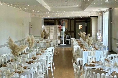 Centre de table floral avec fleurs séchées et pampas, entouré de couverts et cadeaux emballés sur une nappe blanche.