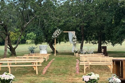 Centre de table floral avec fleurs séchées et pampas, entouré de couverts et cadeaux emballés sur une nappe blanche.