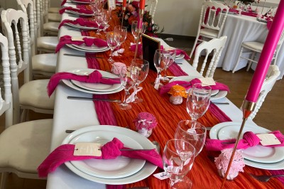 Centre de table floral avec fleurs séchées et pampas, entouré de couverts et cadeaux emballés sur une nappe blanche.