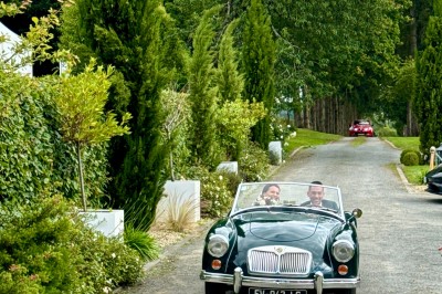 Centre de table floral avec fleurs séchées et pampas, entouré de couverts et cadeaux emballés sur une nappe blanche.