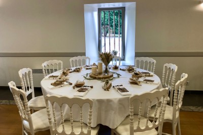 Centre de table floral avec fleurs séchées et pampas, entouré de couverts et cadeaux emballés sur une nappe blanche.