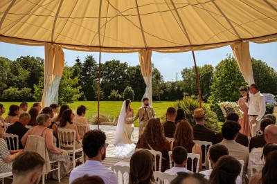 Miniature Location salle Montauban-de-Bretagne (Ille-et-Vilaine) - Manoir de Caslou #94 Mariée avançant sur une allée blanche sous une tonnelle, entourée d'invités assis lors d'une cérémonie en extérieur.