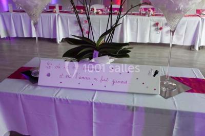 Table de pique-nique en bois sur un sol de gravier, entourée d'arbres dans un cadre naturel.