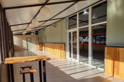 Table de pique-nique en bois sur un sol de gravier, entourée d'arbres dans un cadre naturel.