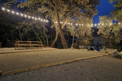 Table de pique-nique en bois sur un sol de gravier, entourée d'arbres dans un cadre naturel.