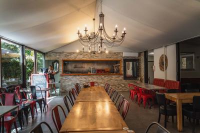 Miniature Location salle Saint-Priest (Rhône) - Le 21 #15 Salon de jardin extérieur avec canapé en palettes, table basse et plantes, devant une façade rouge avec porte en bois.