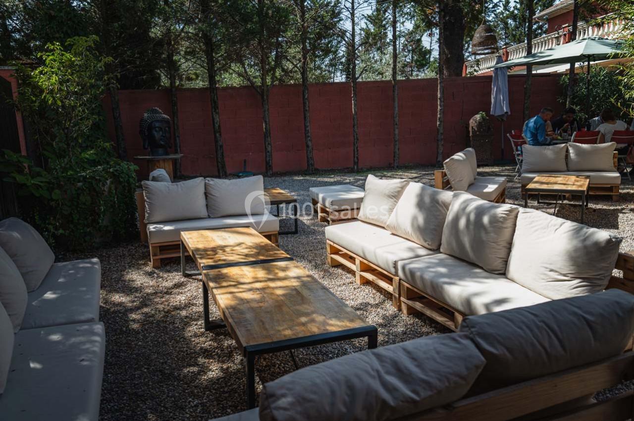 Mobilier de salon extérieur avec canapés en palettes et tables basses, installé dans une cour ombragée.