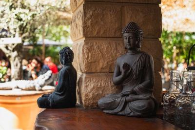 Miniature Location salle Saint-Priest (Rhône) - Le 21 #18 Salon de jardin extérieur avec canapé en palettes, table basse et plantes, devant une façade rouge avec porte en bois.