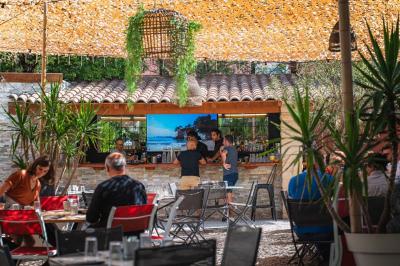 Miniature Location salle Saint-Priest (Rhône) - Le 21 #10 Salon de jardin extérieur avec canapé en palettes, table basse et plantes, devant une façade rouge avec porte en bois.