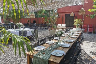 Miniature Location salle Saint-Priest (Rhône) - Le 21 #6 Salon de jardin extérieur avec canapé en palettes, table basse et plantes, devant une façade rouge avec porte en bois.