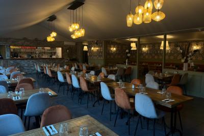 Miniature Location salle Saint-Priest (Rhône) - Le 21 #11 Salon de jardin extérieur avec canapé en palettes, table basse et plantes, devant une façade rouge avec porte en bois.