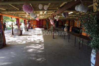 Salle de réception décorée avec des tables dressées, des fleurs et des voilages suspendus sous un plafond en bois.