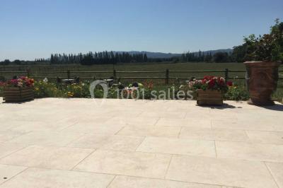 Salle de réception décorée avec des tables dressées, des fleurs et des voilages suspendus sous un plafond en bois.
