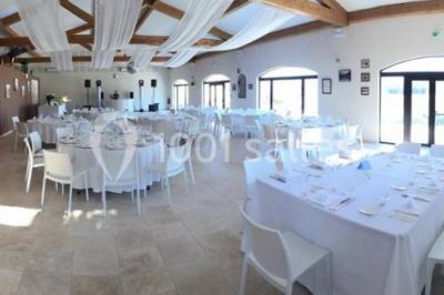 Salle de réception décorée avec des tables dressées, des fleurs et des voilages suspendus sous un plafond en bois.