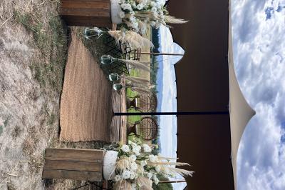 Salle de réception décorée avec des tables dressées, des fleurs et des voilages suspendus sous un plafond en bois.