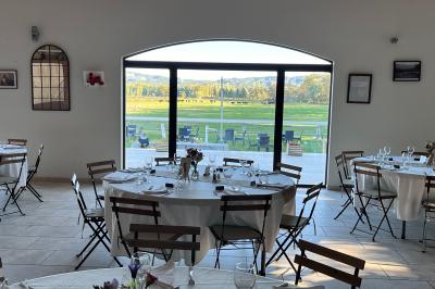 Salle de réception décorée avec des tables dressées, des fleurs et des voilages suspendus sous un plafond en bois.