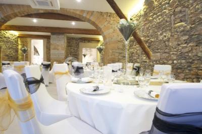 Tente blanche avec mobilier de jardin noir sur tapis rouge, installée devant une entrée vitrée d'un bâtiment beige.