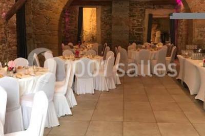 Tente blanche avec mobilier de jardin noir sur tapis rouge, installée devant une entrée vitrée d'un bâtiment beige.
