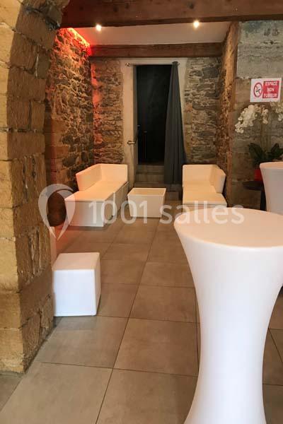 Salle en pierre avec mobilier blanc moderne, comprenant des canapés, des tables basses et des tables hautes.