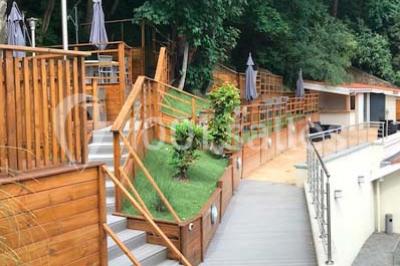 Tente blanche avec mobilier de jardin noir sur tapis rouge, installée devant une entrée vitrée d'un bâtiment beige.