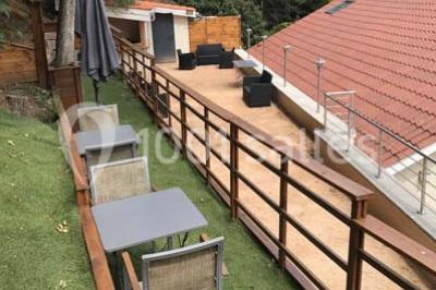 Tente blanche avec mobilier de jardin noir sur tapis rouge, installée devant une entrée vitrée d'un bâtiment beige.