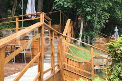 Tente blanche avec mobilier de jardin noir sur tapis rouge, installée devant une entrée vitrée d'un bâtiment beige.