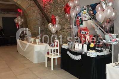 Tente blanche avec mobilier de jardin noir sur tapis rouge, installée devant une entrée vitrée d'un bâtiment beige.