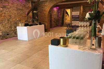 Tente blanche avec mobilier de jardin noir sur tapis rouge, installée devant une entrée vitrée d'un bâtiment beige.