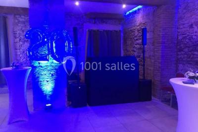 Tente blanche avec mobilier de jardin noir sur tapis rouge, installée devant une entrée vitrée d'un bâtiment beige.