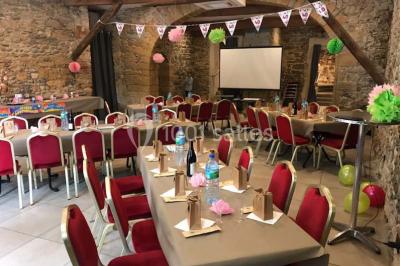 Tente blanche avec mobilier de jardin noir sur tapis rouge, installée devant une entrée vitrée d'un bâtiment beige.