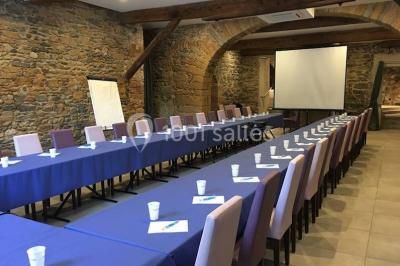 Cuisine professionnelle vide avec plans de travail en inox, évier, étagères ouvertes et réfrigérateurs en arrière-plan.