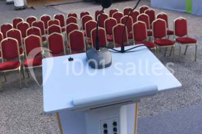 Cuisine professionnelle vide avec plans de travail en inox, évier, étagères ouvertes et réfrigérateurs en arrière-plan.