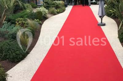 Cuisine professionnelle vide avec plans de travail en inox, évier, étagères ouvertes et réfrigérateurs en arrière-plan.