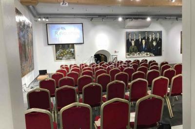 Cuisine professionnelle vide avec plans de travail en inox, évier, étagères ouvertes et réfrigérateurs en arrière-plan.