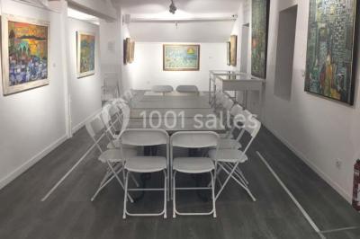 Cuisine professionnelle vide avec plans de travail en inox, évier, étagères ouvertes et réfrigérateurs en arrière-plan.