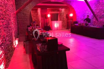 Cuisine professionnelle vide avec plans de travail en inox, évier, étagères ouvertes et réfrigérateurs en arrière-plan.