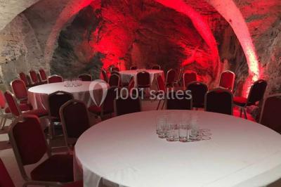 Cuisine professionnelle vide avec plans de travail en inox, évier, étagères ouvertes et réfrigérateurs en arrière-plan.