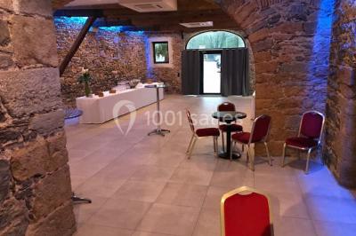 Cuisine professionnelle vide avec plans de travail en inox, évier, étagères ouvertes et réfrigérateurs en arrière-plan.