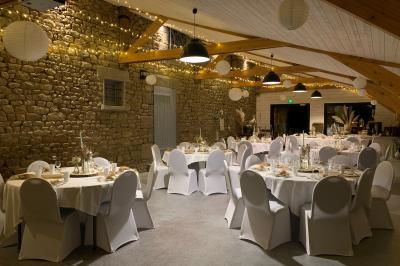Un couple de mariés ému écoute un joueur de cornemuse, entouré d'invités applaudissant dans une salle lumineuse.
