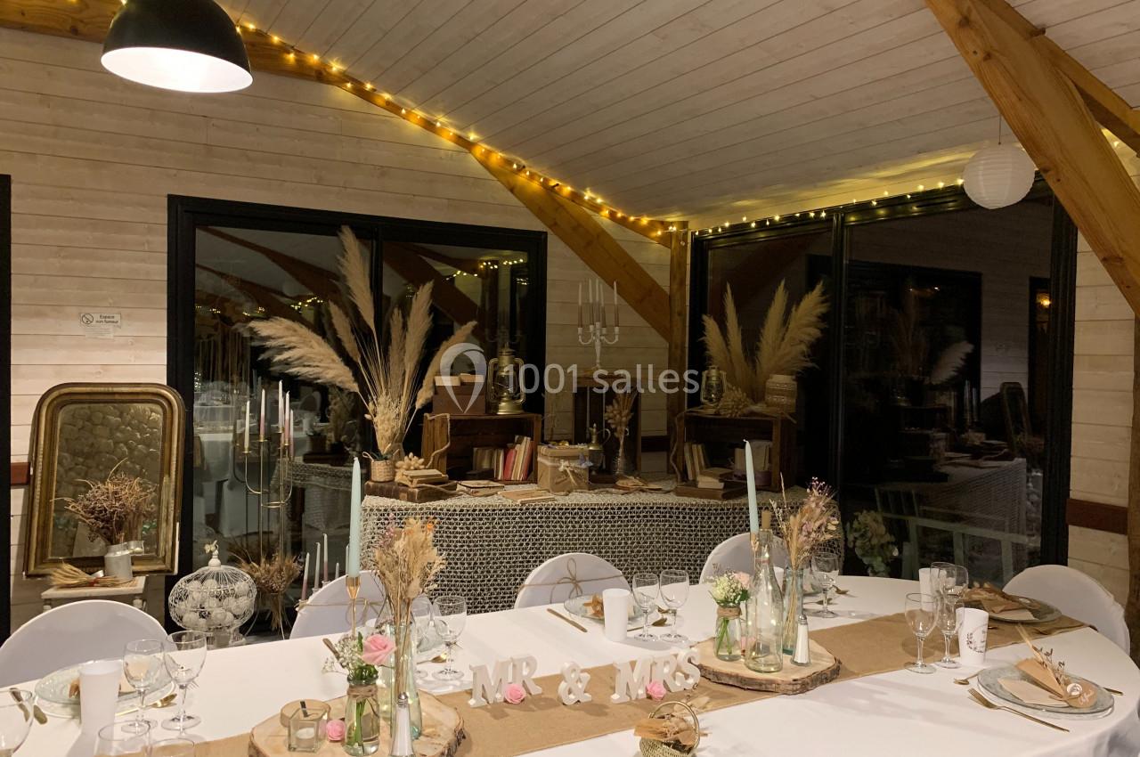 Salle décorée pour un mariage avec table dressée, pampas, guirlandes lumineuses et éléments rustiques.