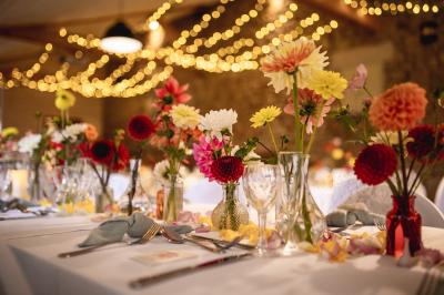 Un couple de mariés ému écoute un joueur de cornemuse, entouré d'invités applaudissant dans une salle lumineuse.