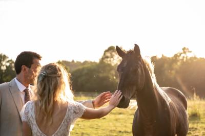 Un couple de mariés ému écoute un joueur de cornemuse, entouré d'invités applaudissant dans une salle lumineuse.